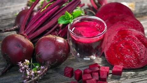 Segelas jus bit berwarna ungu kemerahan yang pekat. Jus bit kaya akan nitrat alami yang efektif untuk menurunkan tekanan darah pada ibu hamil.