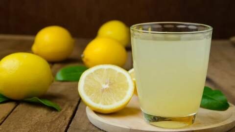 Segelas air lemon segar dengan irisan buah lemon di sampingnya. Minuman ini dapat membantu menjaga elastisitas pembuluh darah untuk kontrol tekanan darah yang lebih baik selama kehamilan.
